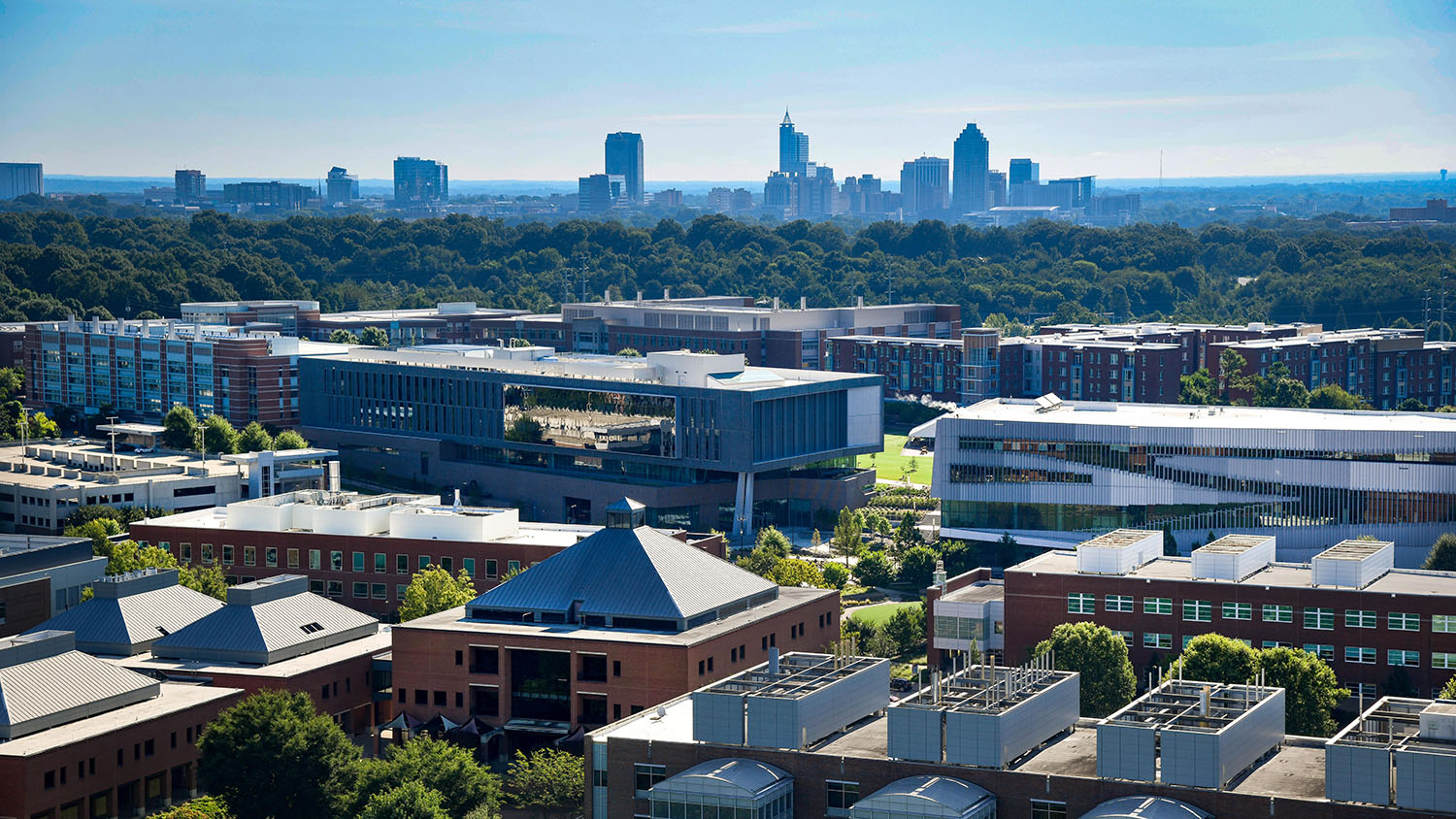 A photo highlighting the engineering buildings on Centennial Campus, in relation to downtown Raleigh skyline.