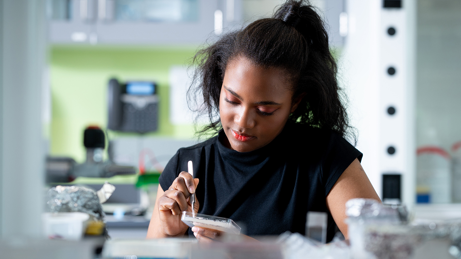 A researcher uses a small handheld tool to manipulate a sample in a petri dish.