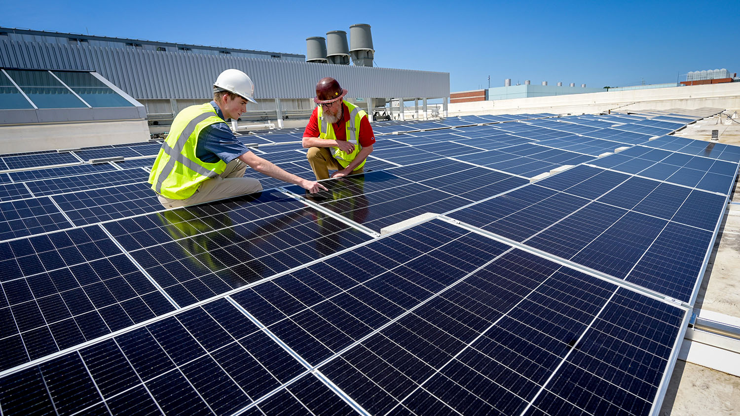 A student intern and a construction manager inspect solar panels installed on the Fitts-Woolard Engineering Building on Centennial Campus.